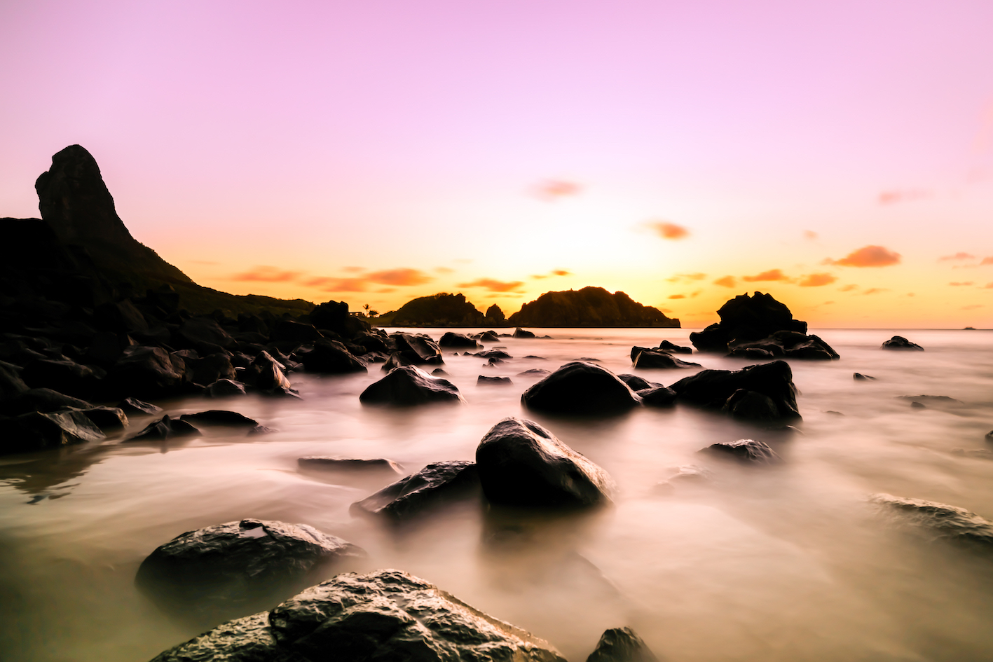 Beautiful Long Exposure in a purple Sunset view on the rocks formation and Morro do Pico at Cachorro Beach, Fernando de Noronha Marine National Park , a Unesco World Heritage site, Pernambuco, Brazil